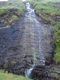 A sheet of water falling down a slab of rock.