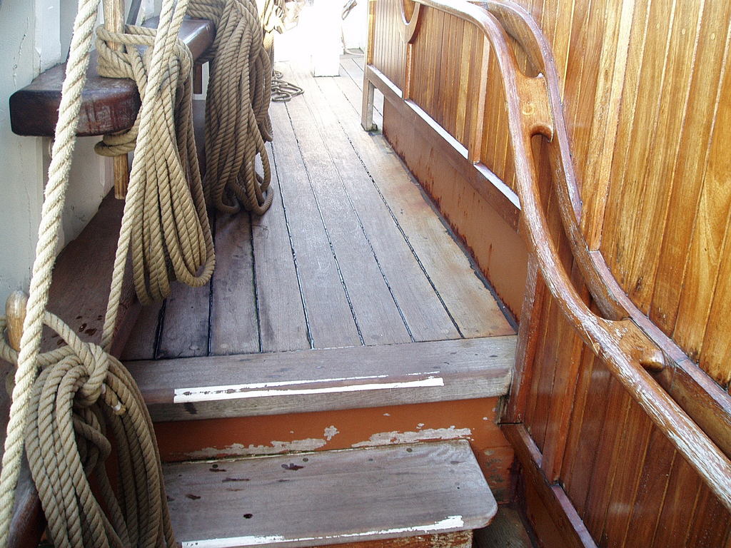 The curved handrail leading towards the stern of the ship.